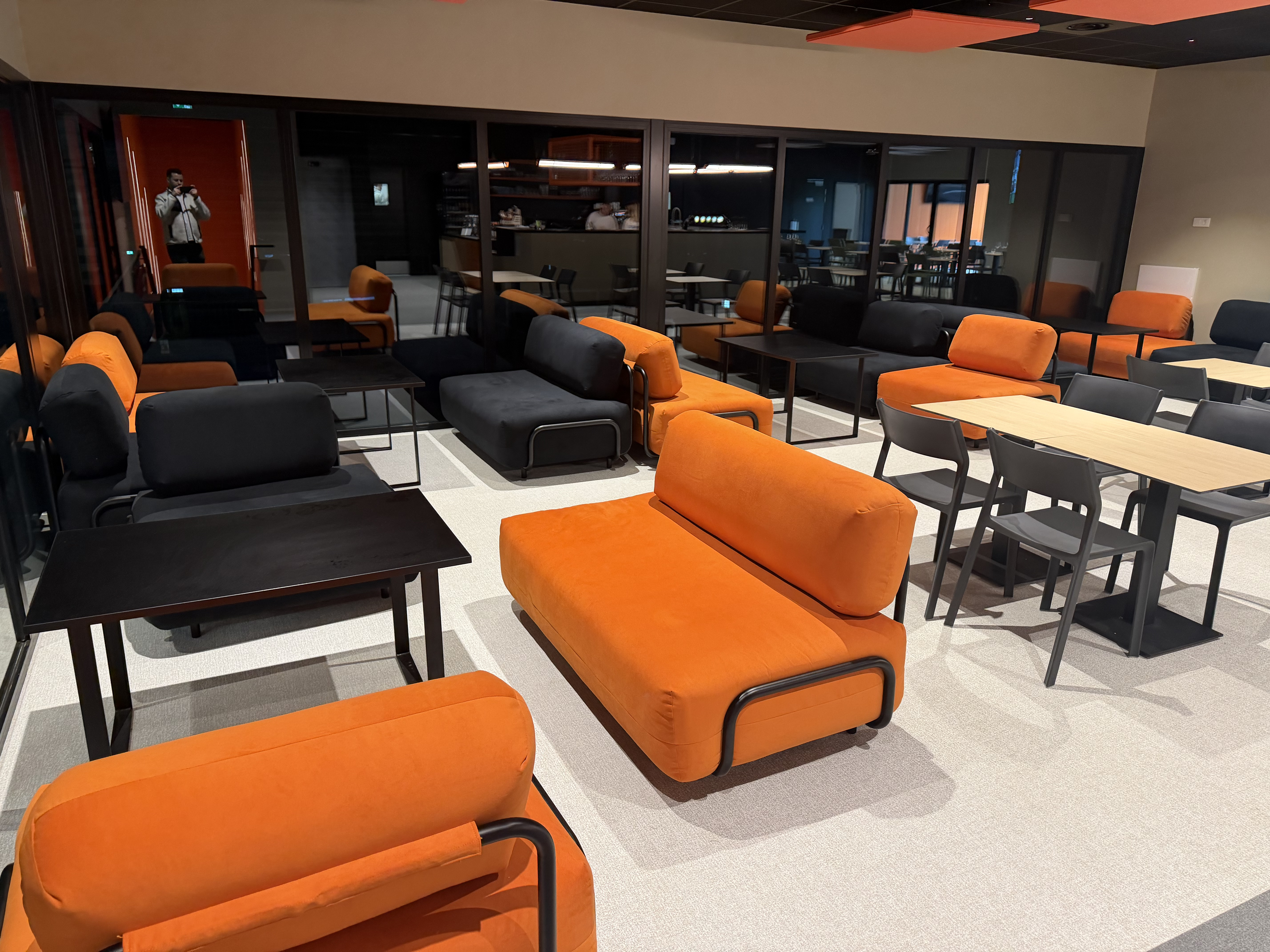 Espace lounge avec canapés orange et anthracite